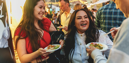 Two Food Bowl attendees holding food and chatting