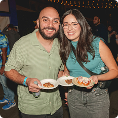 Two attendees smiling and holding plates of food from vendors