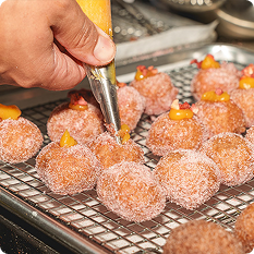 Close up shot of vendor piping filling into pastry