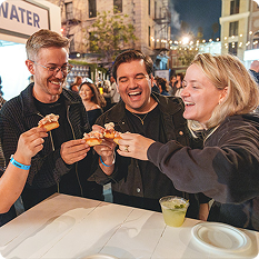 Four Food Bowl attendees toasting with mini lobster rolls